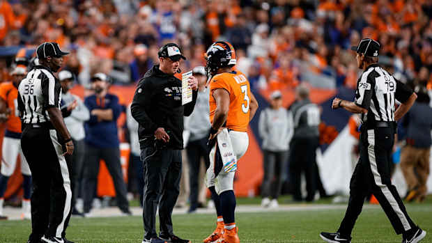 Denver Broncos head coach Nathaniel Hackett talks with quarterback Russell Wilson (3) as side judge Anthony Jeffries (36) and down judge Kent Payne (79) look on in the fourth quarter against the Indianapolis Colts at Empower Field at Mile High.